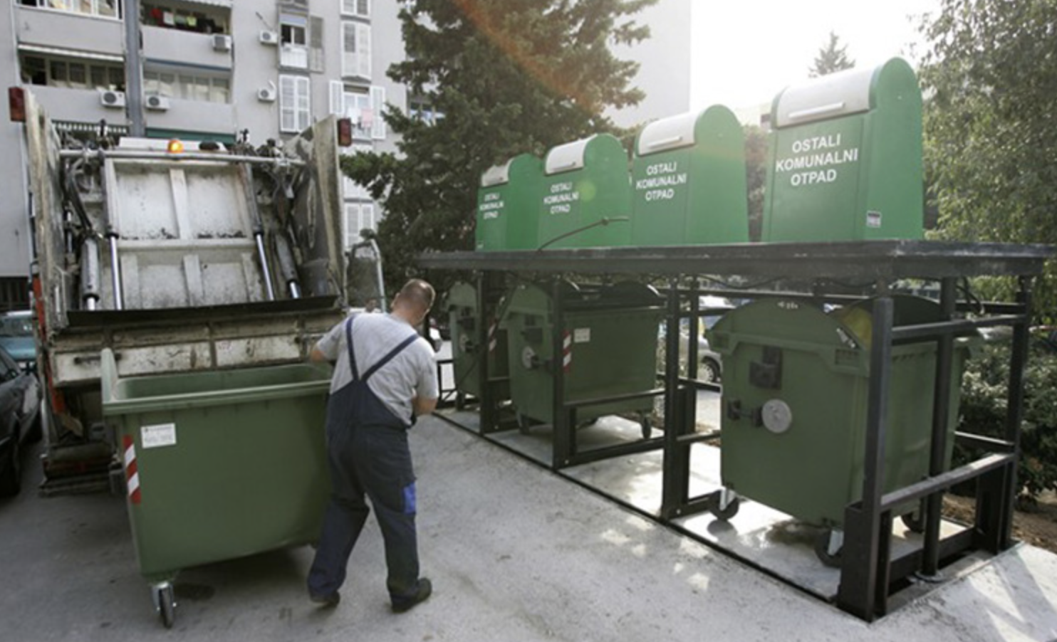 Waste collection truck emptying a bin beside a row of green EUROTIM underground containers
